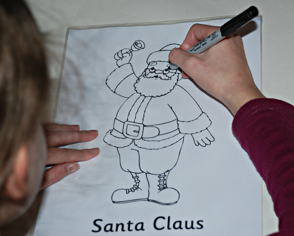 Tracing over the Santa Claus colouring page onto a laminating sleeve