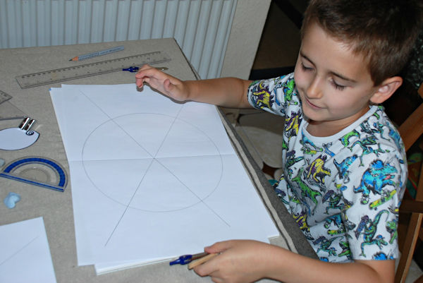 Using his geometry set to create the lines for the mandala