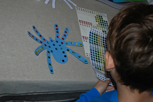Decorating his spiders with jewelled stickers
