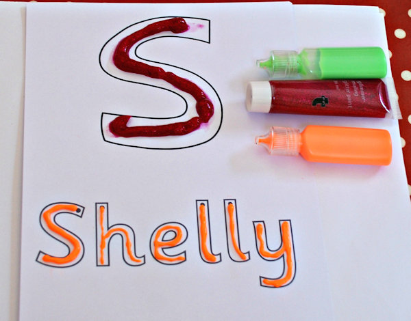 Squeezing out glitter paint or puffy paint to trace the letters