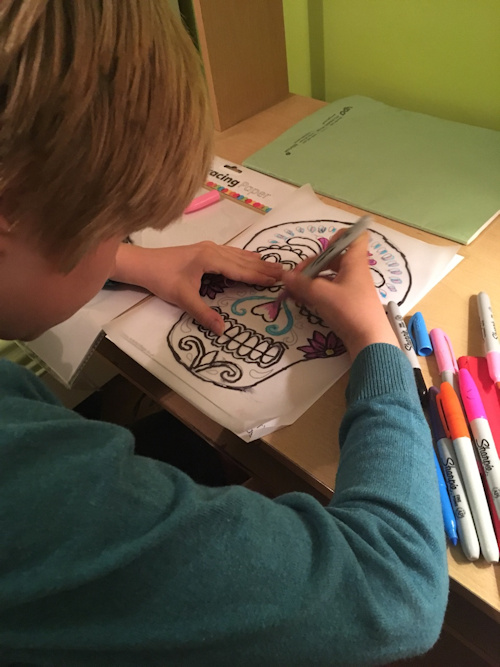 Tracing the edges and then colouring in a sugar skull colouring page