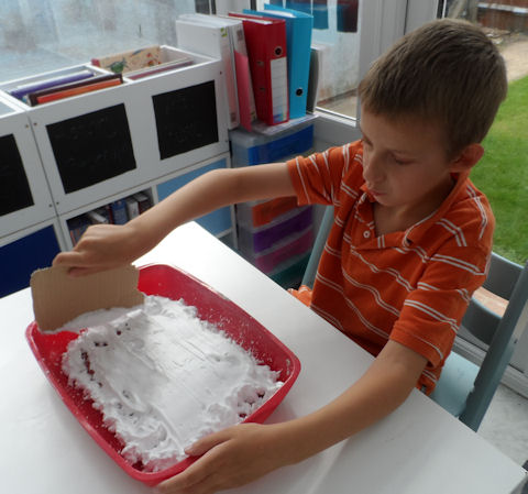 Smoothing the shaving foam down with a piece of card